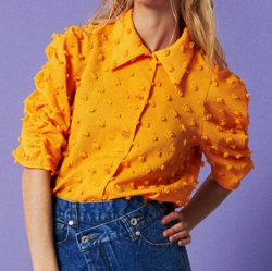 オレンジのポンポン付きシャツ